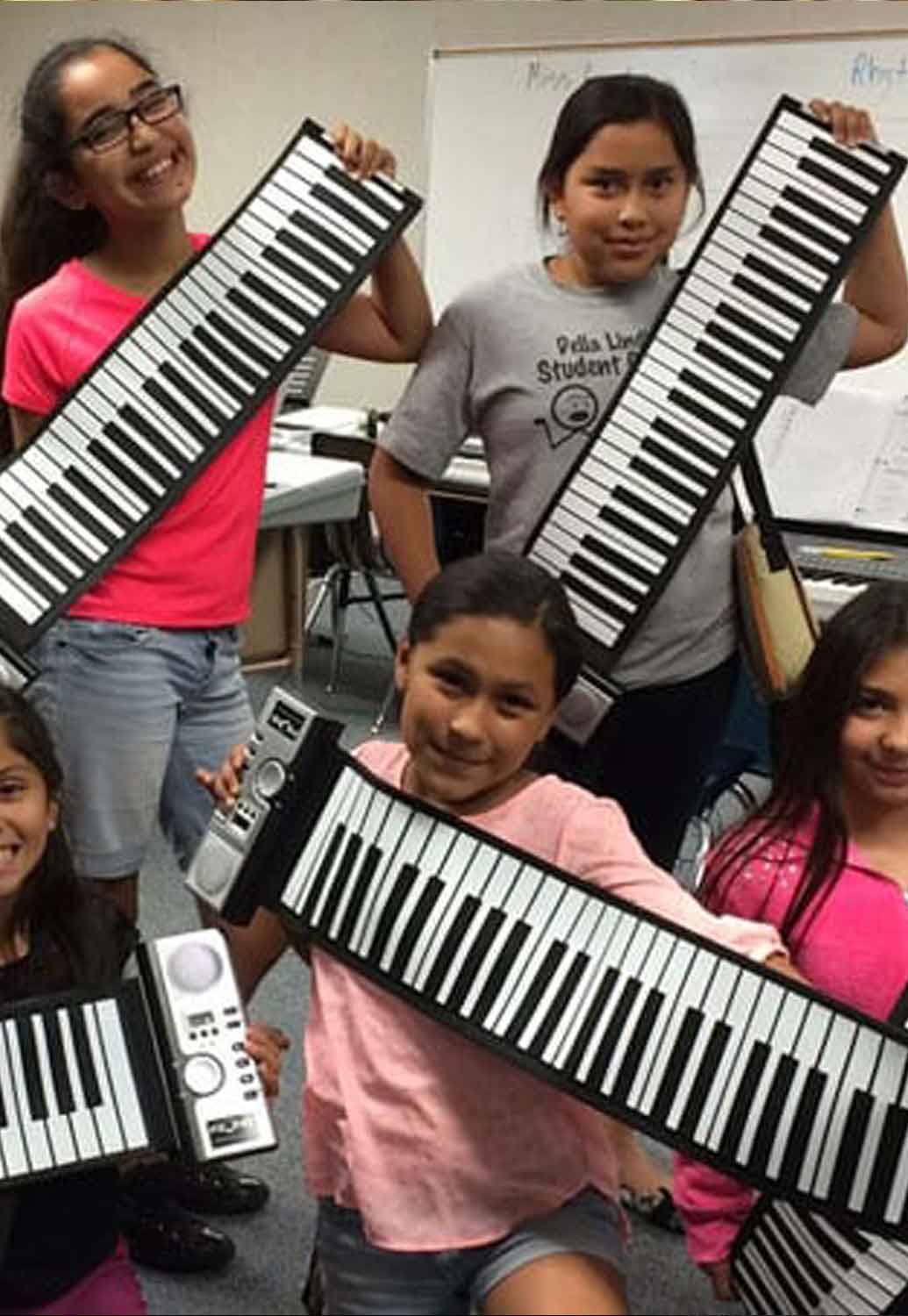 Girls holding piano keyboards in a class setting